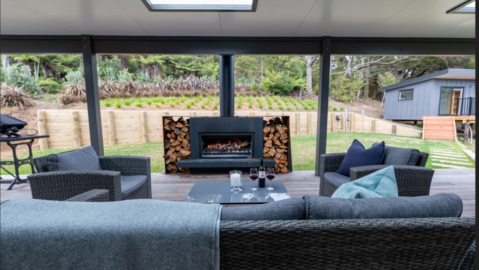Back deck, back lawn and fireplace with cabin in the background which ha a queen room and a bunk room