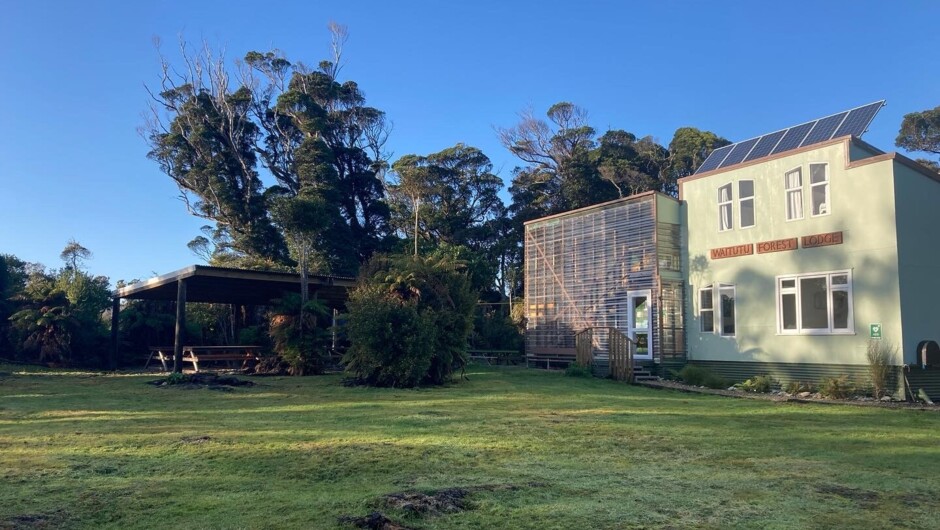 The Waitutu Forest Lodge with the sun setting over the forest