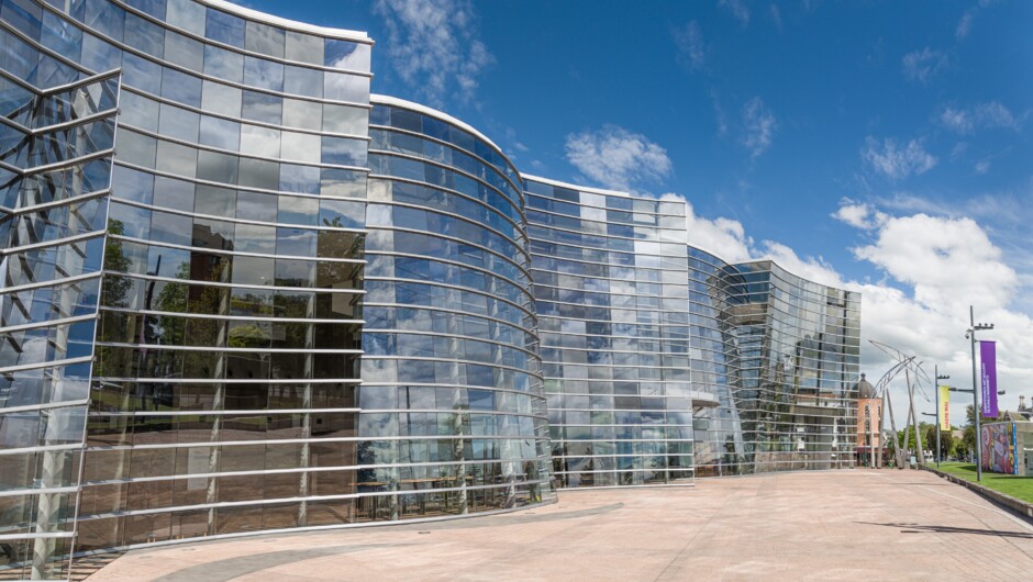Featuring a spectacular flowing glass and metal façade that evokes the sinuous form of the koru and Christchurch's River Avon, the building houses nine exhibition areas, a reference library, auditorium, education workrooms, restaurant, shops and extensive