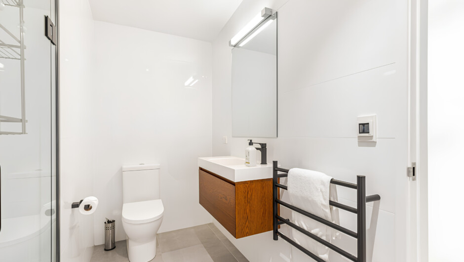 Bright toilet and bath with towels, toilet paper, body wash, shampoo, and conditioner