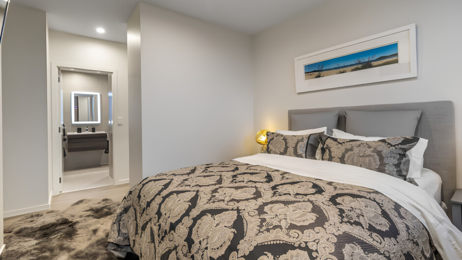 Queen bed complete with a bedside reading lamp, a private TV, and large windows