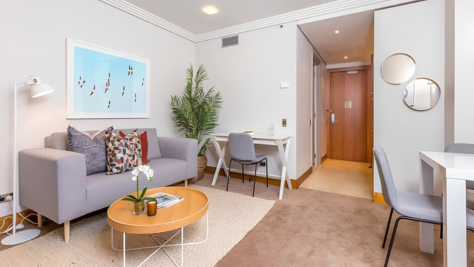 Open-plan living space with couch, work desk, and 3-seater dining table