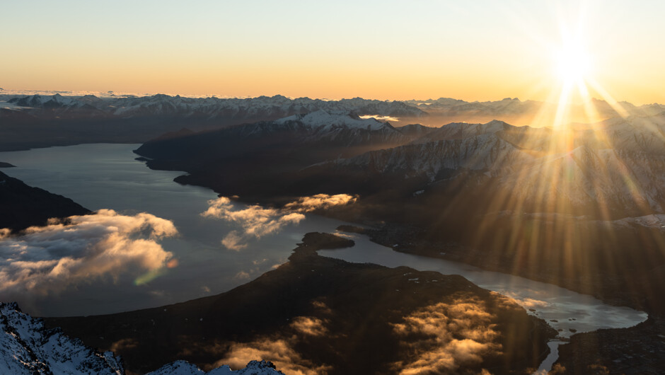 Golden hour light stretching across the Wakatipu Basin and surrounding peaks