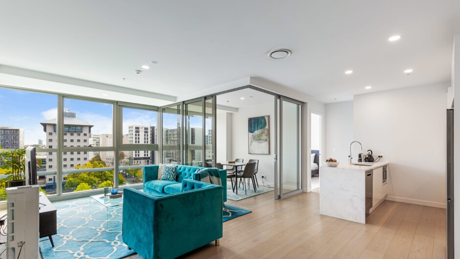 Sun-drenched living area featuring panoramic city views, plush seating, and an entertainment system equipped with a 4K Google TV and local Freeview Digital.