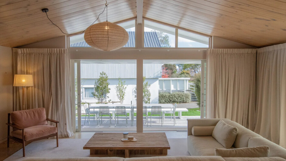 The open-plan living area with timber ceilings, opening onto the deck