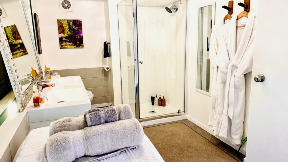 The Ngahere Suite bathroom with hair dryer, body products, robes and a twin basin.