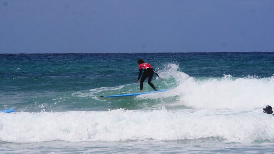 Riding a wave at Sumner Beach, one of the best places to learn to surf in Christchurch.