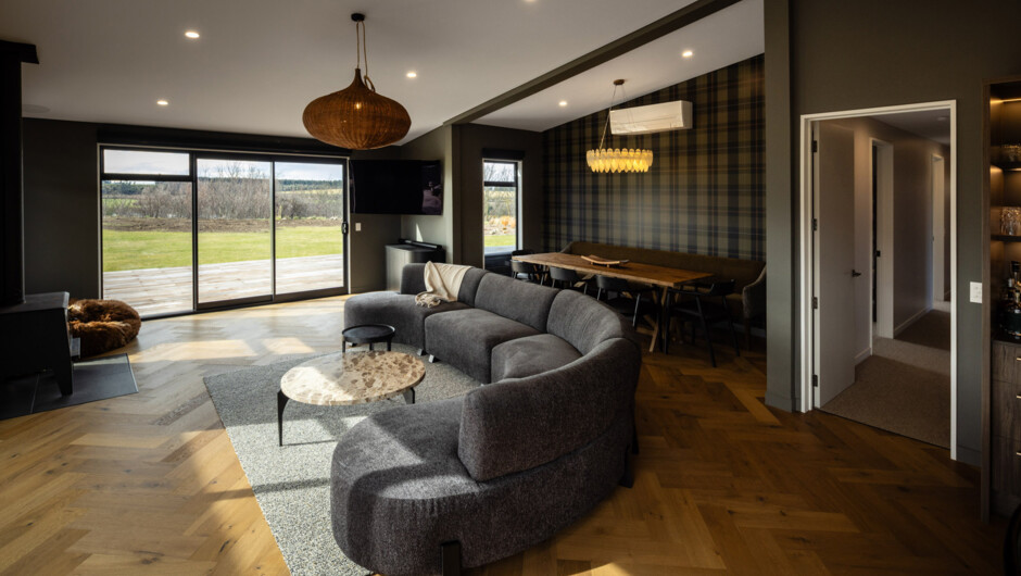 Open plan living with fireplace and floor to ceiling windows that frame Mt Peel and open out to the alfresco dining area with covered BBQ.