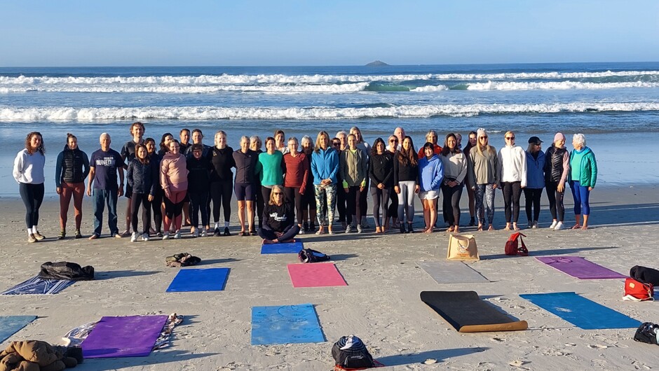 Sunrise Yoga on St Clair Beach during the Wild Dunedin New Zealand Festival of Nature. White Island on the horizon and a vibrant group enjoying yoga in the sunshine.