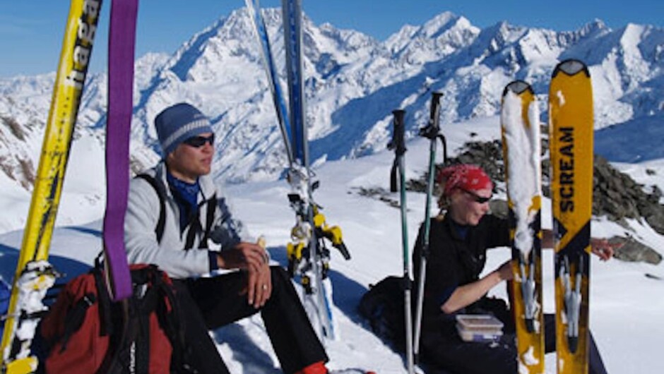 Alpine ski tourers pause for lunch after a ski ascent of Hochstetter Dome at the top of the Tasman Glacier. Mount Cook in the background