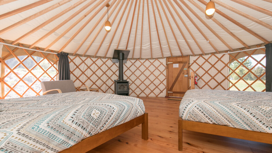 A double queen Yurt room interior with a wood fire & electric heating.