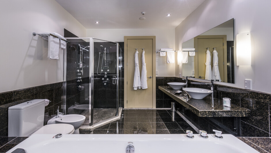 Marbled bathroom featuring a double sized indoor spa and a shower with twin massage heads